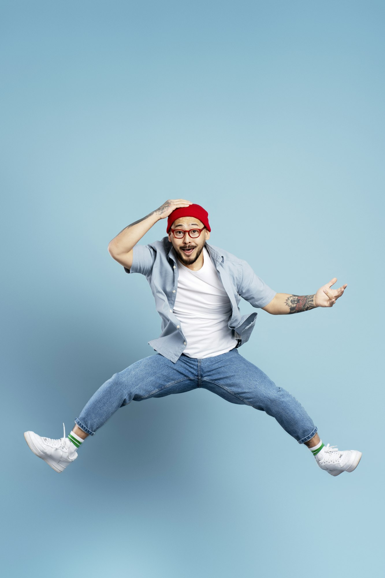 Excited asian man jumping high, having fun isolated on blue background